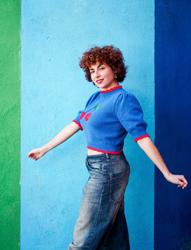 Smiling redhead woman walking outdoors by a colorful wall