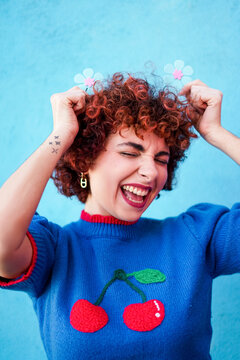 Redhead laughing with flower clips on a blue background