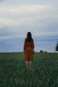 Woman standing in green corn field at sunset