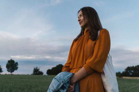 Smiling woman holding denim pants in field