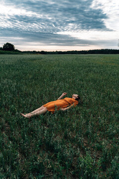 Woman relaxing in corn field at sunset