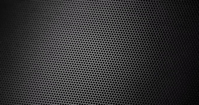 Black Perforated Metal Mesh. Smooth slow movement across extreme close-up of dark perforated metal grid with dramatic side lighting.