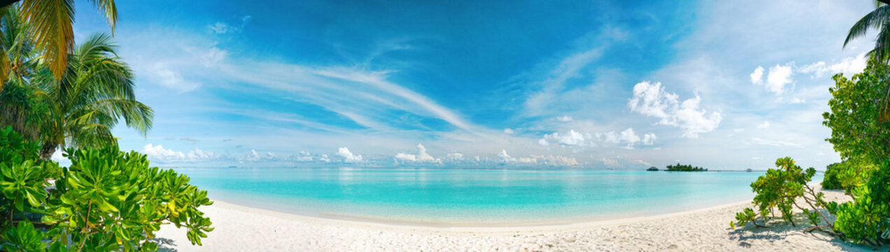 Ultra-wide panoramic nature landscape of a secluded tropical beach in the Maldives.  An ideal spring and summer paradise travel background.