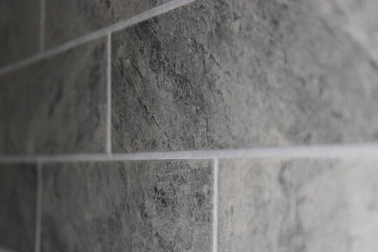 Grey stone texture wall tiles with white grout lines close up