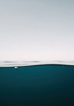 Clear atmospheric sky and water surface split creating a minimal background for aquatic lifestyle branding, spa editorial and refreshing beverage advertising