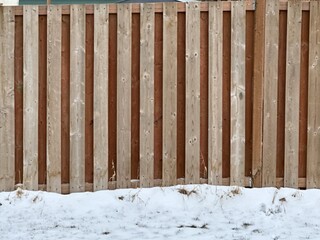 Fototapeta premium Wood privacy fence detail with vertical boards showing residential fencing construction in winter