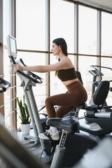 Fototapeta premium Woman exercising on stationary bike in modern gym