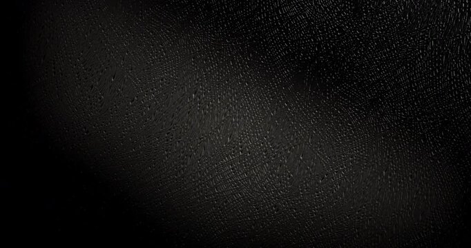 Slow Rotation Over Black Texture. Smooth slow rotation across extreme close-up of fine black pebbled surface with dramatic side lighting.