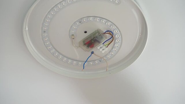Close up of electricians hands installs ceiling LED lamp on ceiling. Current check. Installation light