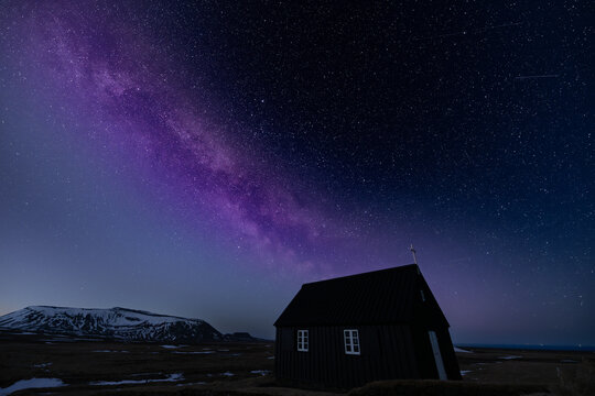 View of a dark and mysterious church beneath the celestial tapestry of the Milky Way, a symphony of purple and blue hues, Krysuvikurkirkja, Hafnarfjardarkaupstadur, Iceland.