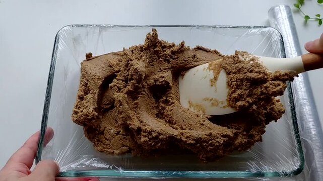 The man puts the halva into the mold with a spatula, preparing it. The process of making homemade halva. Sunflower halva.