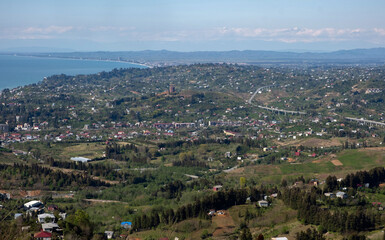 Fototapeta premium Aerial view of a coastal city and elevated highway bridge winding through green hills