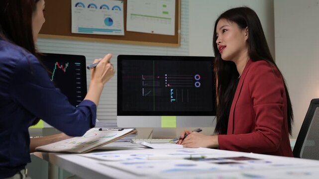 Financial analysts discussing stock market data in a meeting, analyzing financial charts and stock market data on documents and computer screens.