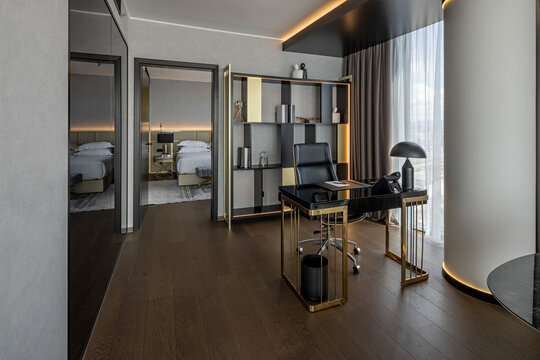 Modern luxury home office with sleek desk, elegant shelving, warm ambient lighting, and bedroom view through open doorway