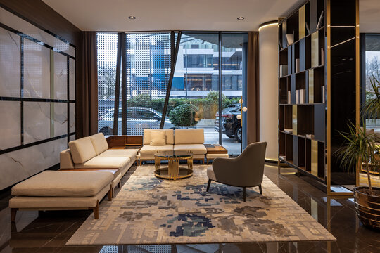 Luxury modern hotel lobby interior with elegant seating area, marble floors, warm lighting, and large glass windows