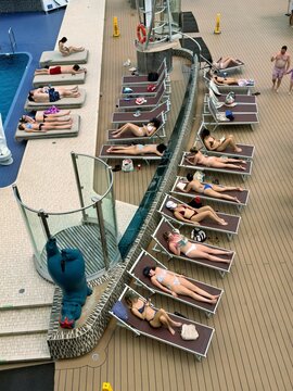 Miami, United States - 16 March 2026: View of passengers relaxing on lounge chairs across a sun-drenched cruise ship deck, with the inviting blue pool nearby.