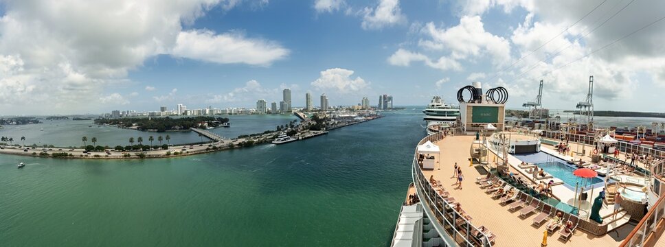 Miami, United States - 16 March 2026: View of the bustling Port Miami and its vibrant city skyline from a sun-drenched cruise ship deck, contrasting with serene turquoise waters.