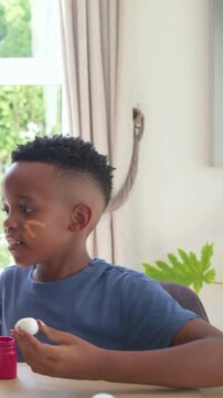 Vertical video: Painting boy painting egg at home, blue tee father joining, bonding, snapping phone