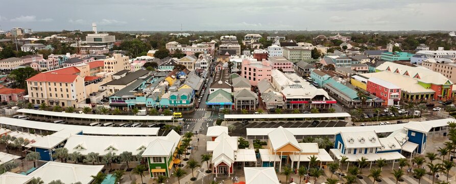Nassau, The Bahamas - 18 March 2026: View of a vibrant downtown area showcasing a medley of pastel-colored buildings under an overcast sky, with modern white structures in the foreground.