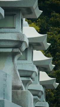 Vertical View of Traditional Stone Lanterns Lined Up in a Row at Japanese Shrine, Cinematic Compression