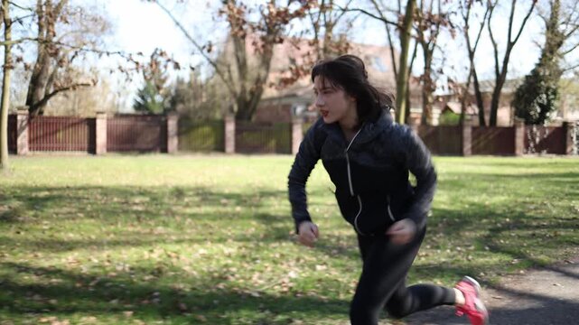 Focused woman in starting stance prepares for run activating muscles improving mobility building healthy habits strong mindset preventive fitness and body awareness outdoors