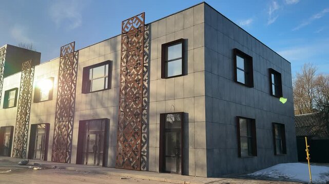 Industrial building with rusted cladding bathed in warm late afternoon sunlight, concrete panels marked by weathered bolts