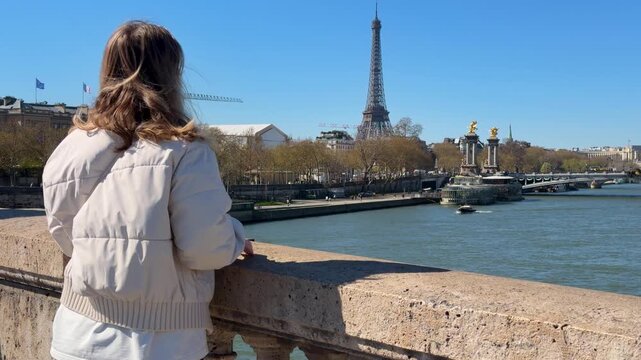 Caucasian woman overlooking eiffel tower from seine bridge paris