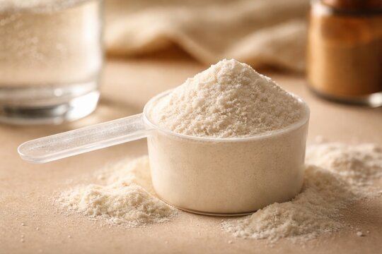 Close up of hydrolyzed collagen powder scoop on beige backdrop featuring wellness additives