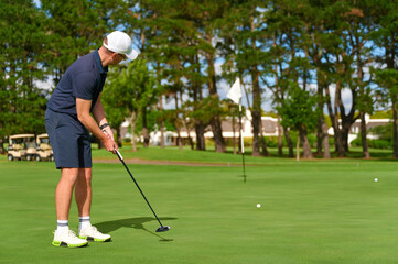 Fototapeta premium Man putting golf ball on green golf course.