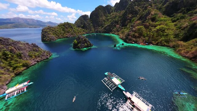 Cinematic FPV drone flight over tropical lagoon with turquoise water, limestone cliffs and boats near Kayangan Lake in Coron, Palawan, Philippines.
