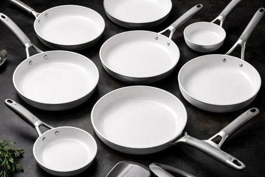 Array of ergonomic white non stick skillets and frying pans displayed on black background