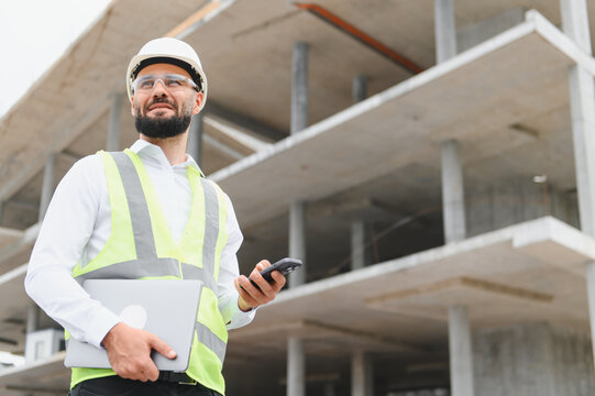 Engineer holding laptop and phone on construction site
