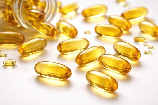 Fish oil omega three and vitamin E nutritional capsules displayed on white backdrop