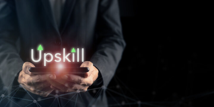 Upskill Concept and Workforce Development Transformation. Holding tablet with glowing Upskill text. Digital learning, employee development and continuous skill growth for future ready workforce.