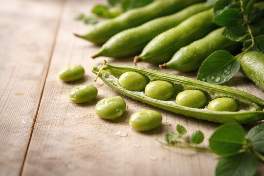 Close perspective of garden fresh fava beans on light wooden backdrop with copy space
