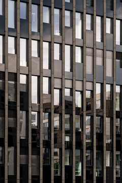 Modern architecture facade features office corporate finance pattern and symmetry as glass windows sit behind dark vertical fins in business tower detail