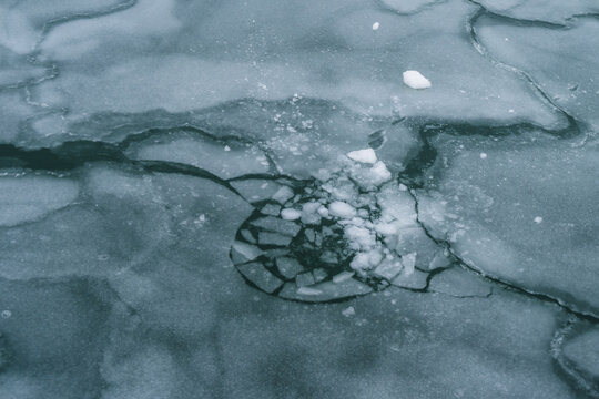View of shattered ice fragments scattered across a frozen expanse, forming a mosaic of textures and tones under the pale winter light, Tallinn, Estonia.