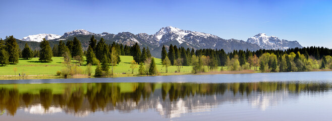 Im beginnenden Frühling spiegeln sich die Allgäuer Alpen auf der Wasseroberfläche des Hegratsrieder Weiher © Wolfilser
