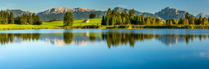 Im Allgäu spiegeln sich die Berge auf der Wasseroberfläche des Huttler Weiher bei Roßhaupten © Wolfilser