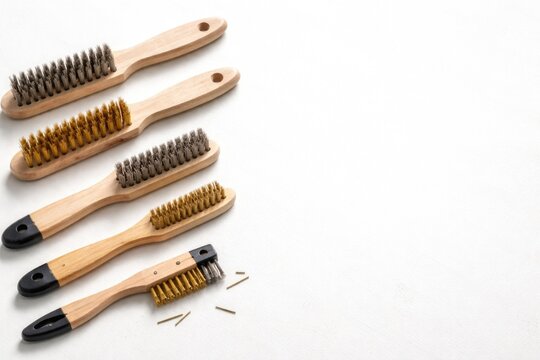 DIY brushes with wooden handles wire and brass types laid on white background with copy space