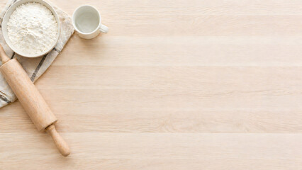 Fototapeta premium Top view of light wooden kitchen counter with baking ingredients and large copy space.
