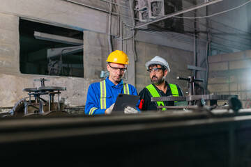 Fototapeta premium Factory Technicians Performing Heavy Machine Maintenance in Traditional Metal Workshop