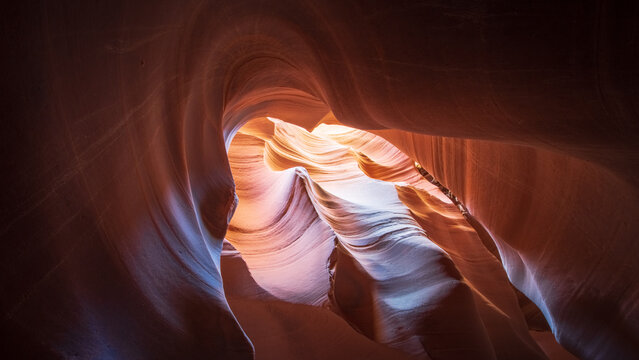 View of swirling sandstone canyon walls bathed in warm light, creating a mesmerizing dance of shadow and illumination, Escalante, Utah, United States.