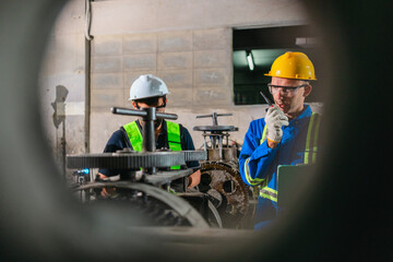 Fototapeta premium Factory Technicians Performing Heavy Machine Maintenance in Traditional Metal Workshop
