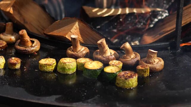 Grilling vegetables, meat, and fish at a fair. Close-up of delicious vegetables grilling over a fire, preparing food for sale at the fair.