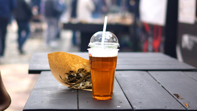 Delicious fried fish at the fair. Beer and fish in a bag on the table. Small dried fish for a snack.