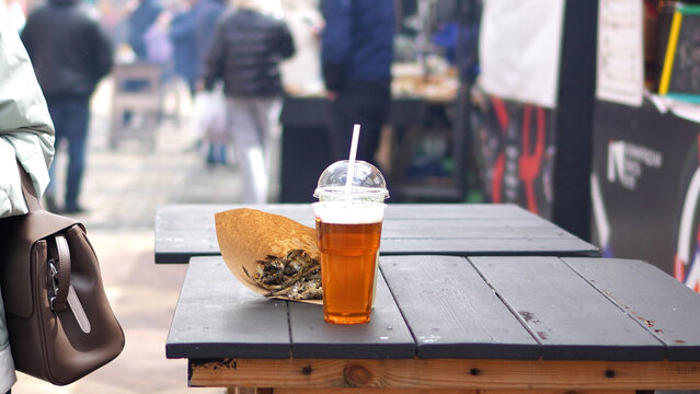 Delicious fried fish at the fair. Beer and fish in a bag on the table. Small dried fish for a snack.