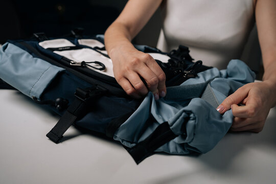 Close-up of traveler female preparing urban backpack, aligning straps and checking compartments, highlighting contemporary design. Concept of organization and travel essentials.
