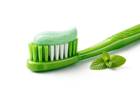 Green plastic toothbrush side perspective displaying mint herbal toothpaste on a pure white background with clipping path illustrating personal care