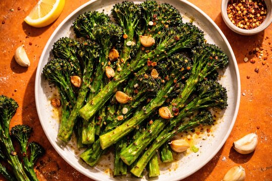 Birds eye perspective of broccolini with garlic grilled served on orange surface